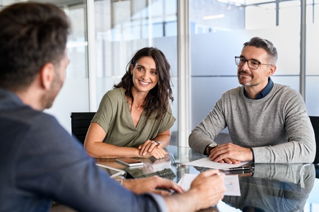 man and woman sitting at a desk talking to someone